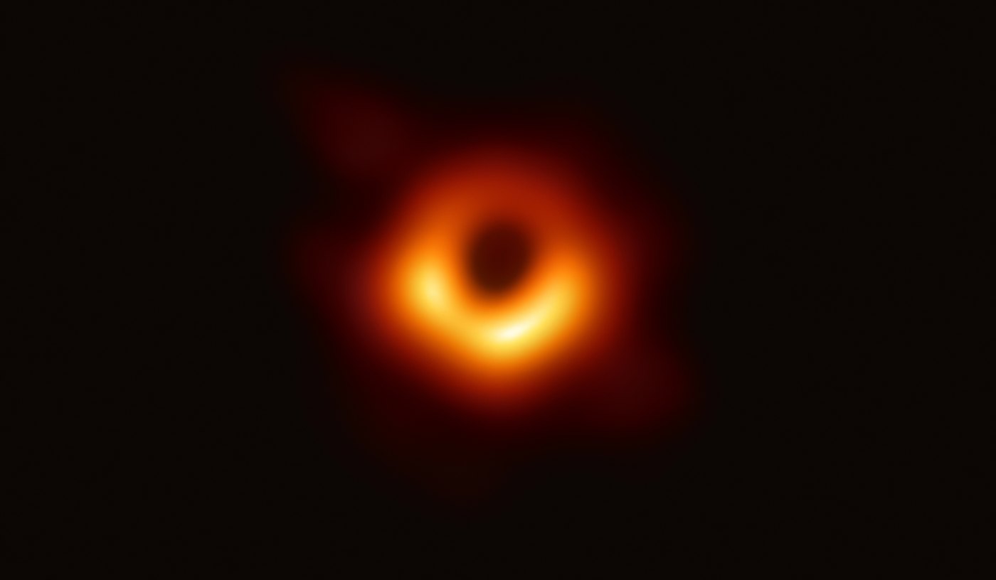 The Event Horizon Telescope's image of M87*: a blurry orange ring around a dark centre, brighter at the bottom.